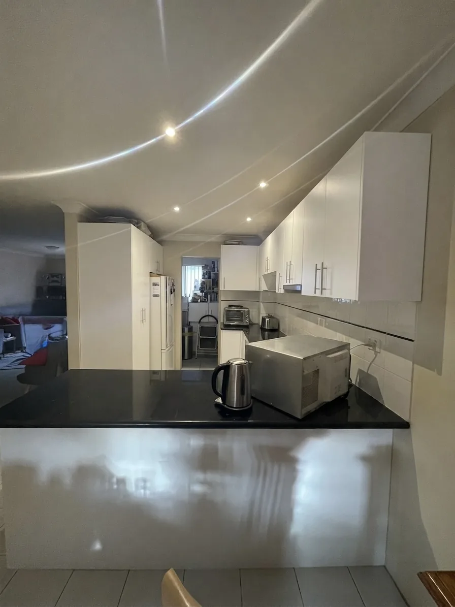 Black benchtop and refinished white cabinetry in an Alexandria apartment kitchen
