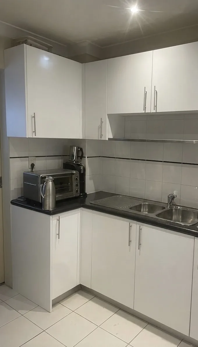 Rebuilt cabinetry run beside the sink where the washing machine cavity was, in Alexandria