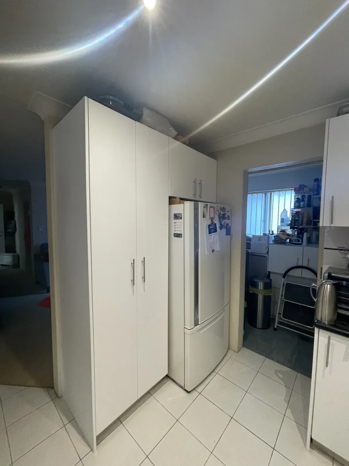 Chrome D-shape handles on refinished white kitchen cabinetry