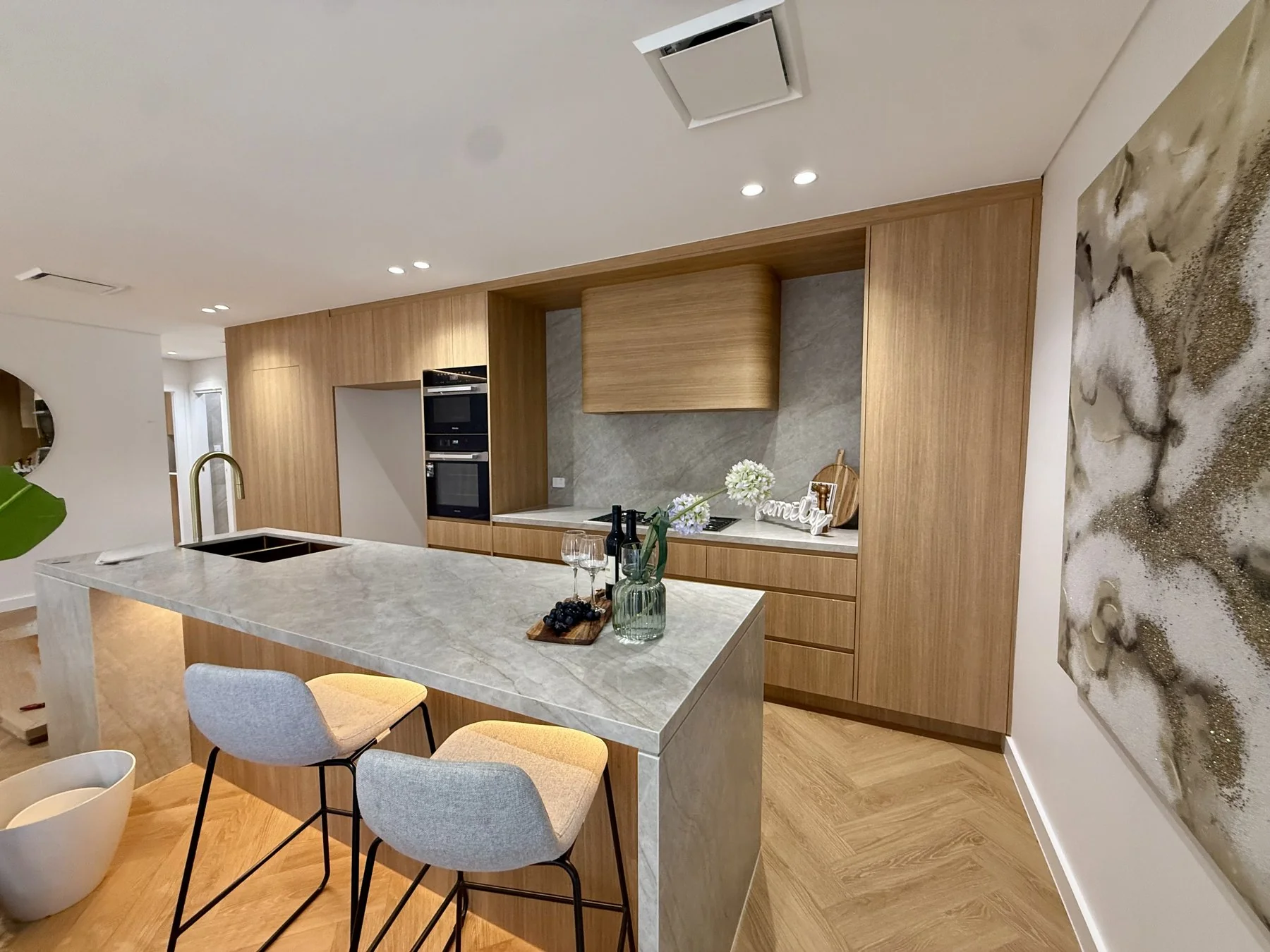 Epping kitchen overview with stone island bench, Sublime Teak cabinetry and living zone beyond