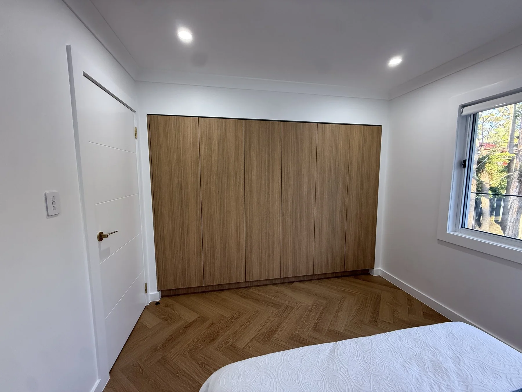 Epping wardrobe overview showing full run of cabinetry across bedroom wall