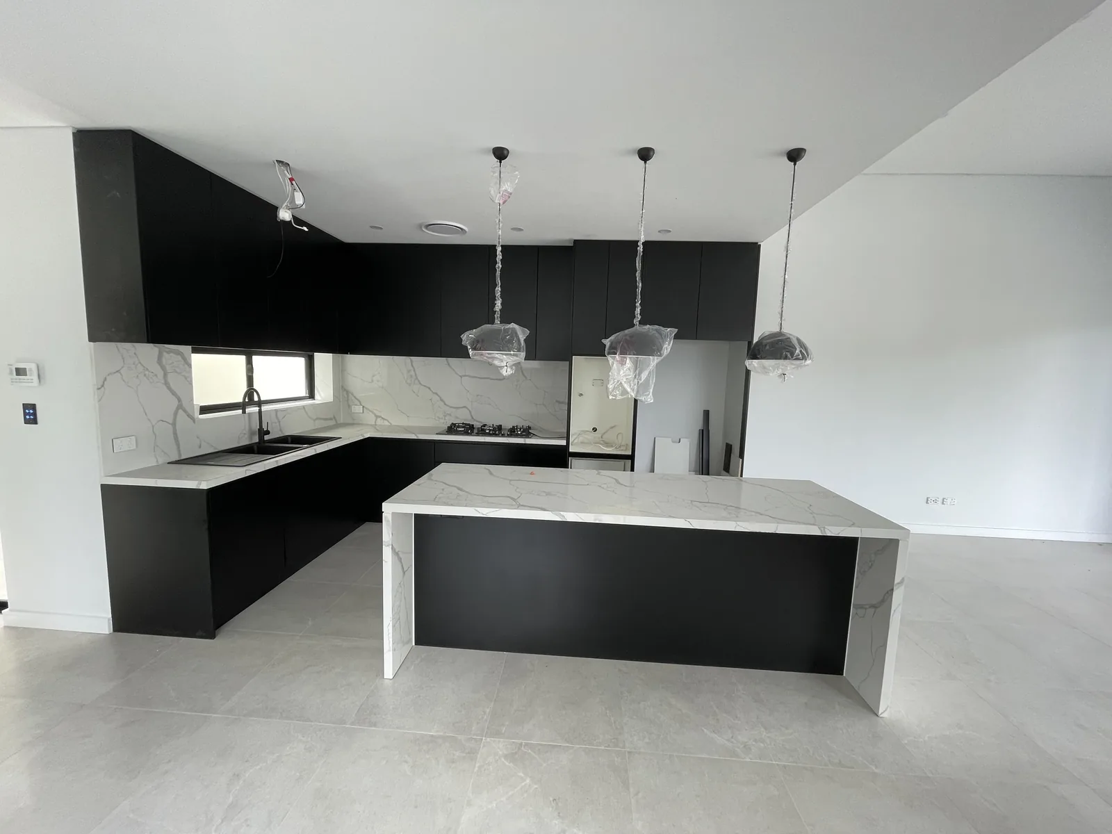 Custom-designed black matt handleless kitchen with Calacatta Maximus stone island in Leichhardt