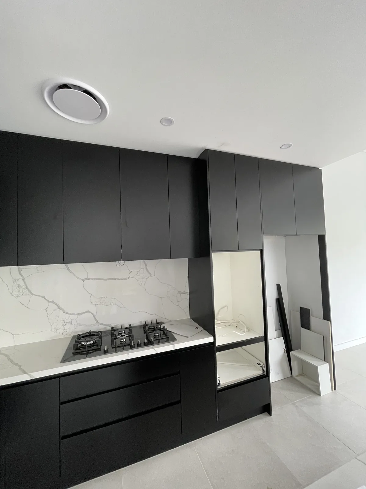 Full-height black matt kitchen cabinetry beside the cooktop in a Leichhardt new build
