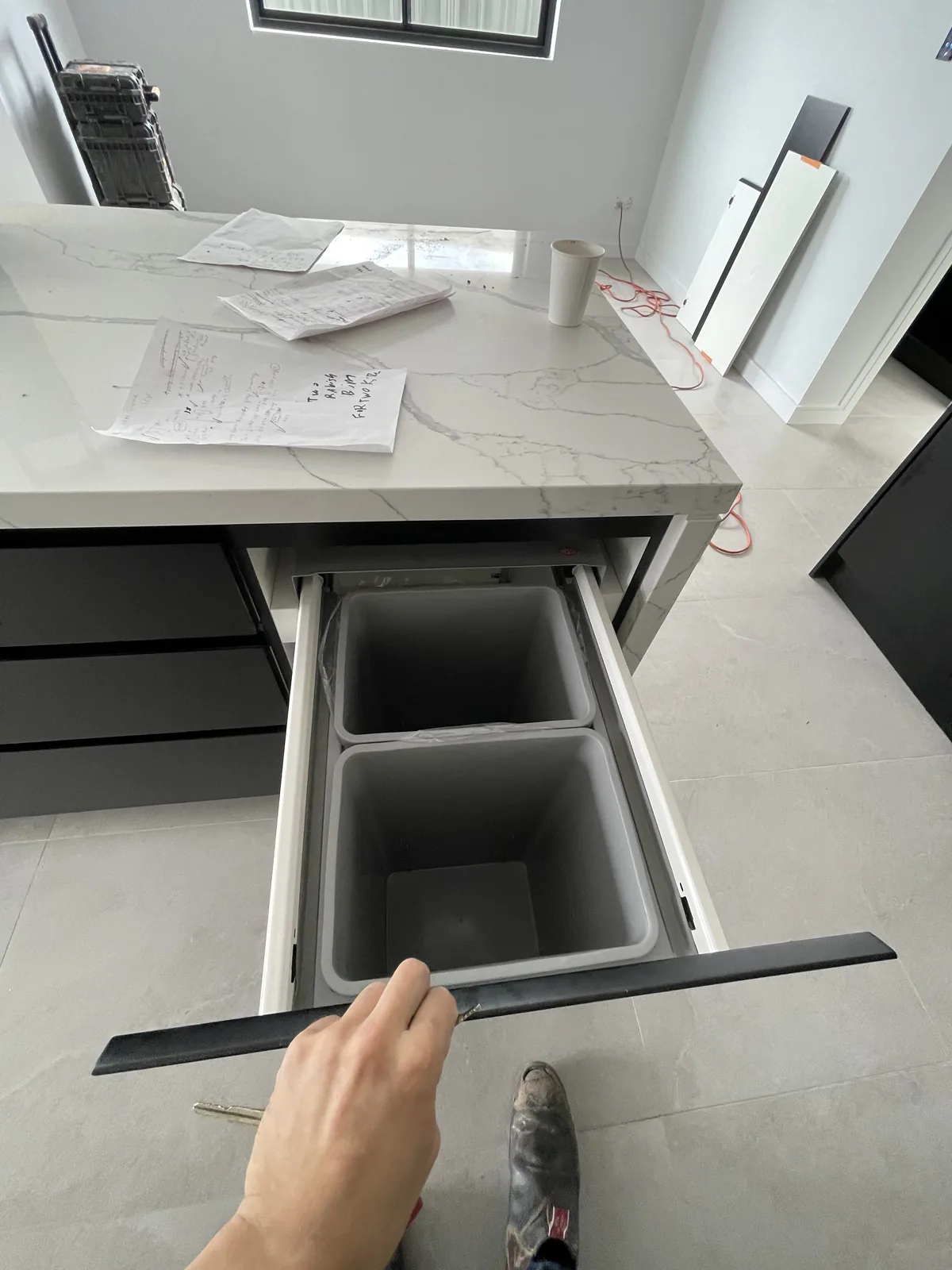 Integrated bin drawer pulled out from a black matt kitchen island on soft-close runners