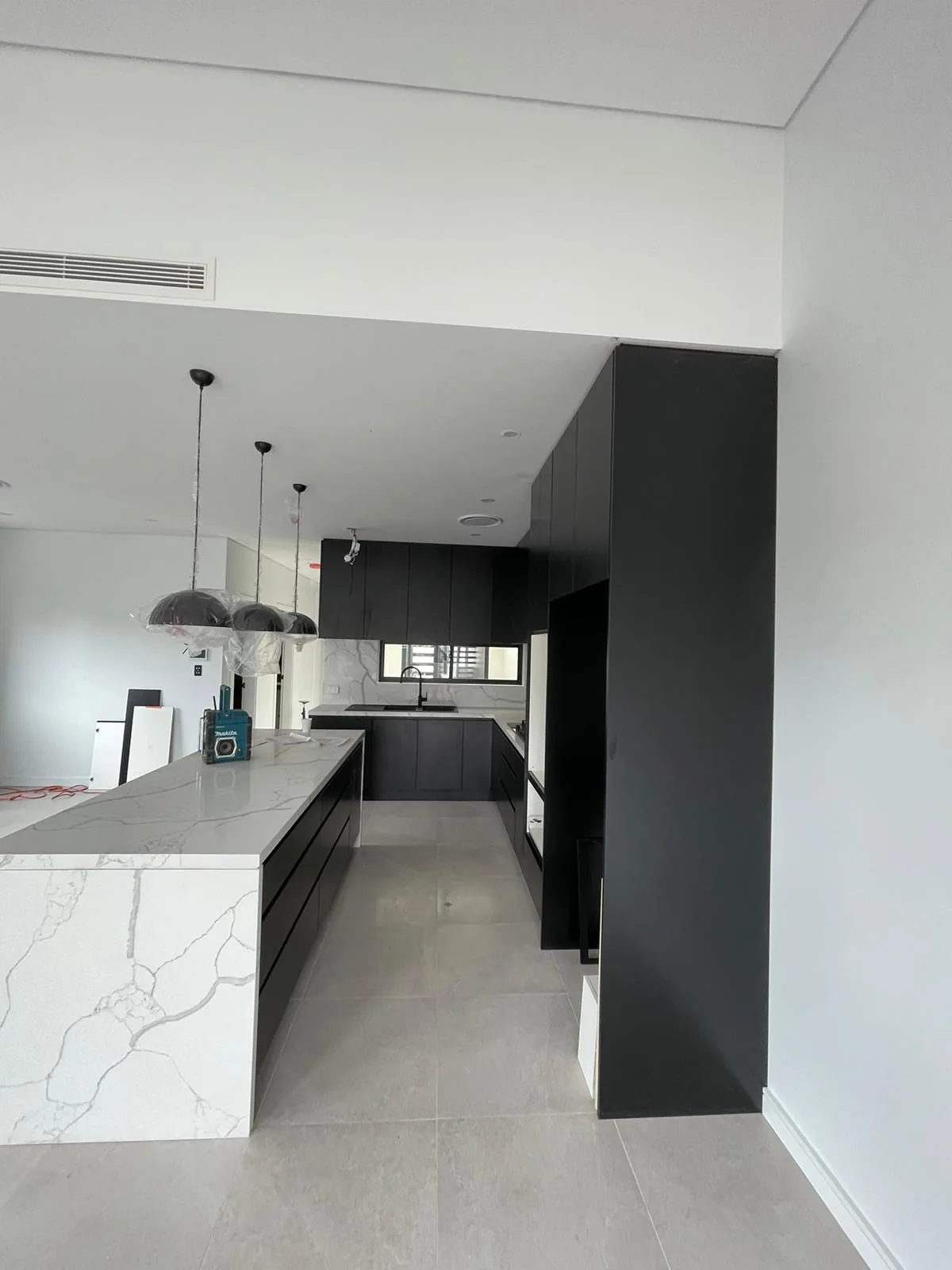 Open plan view of a black matt kitchen with a Calacatta Maximus island in Leichhardt