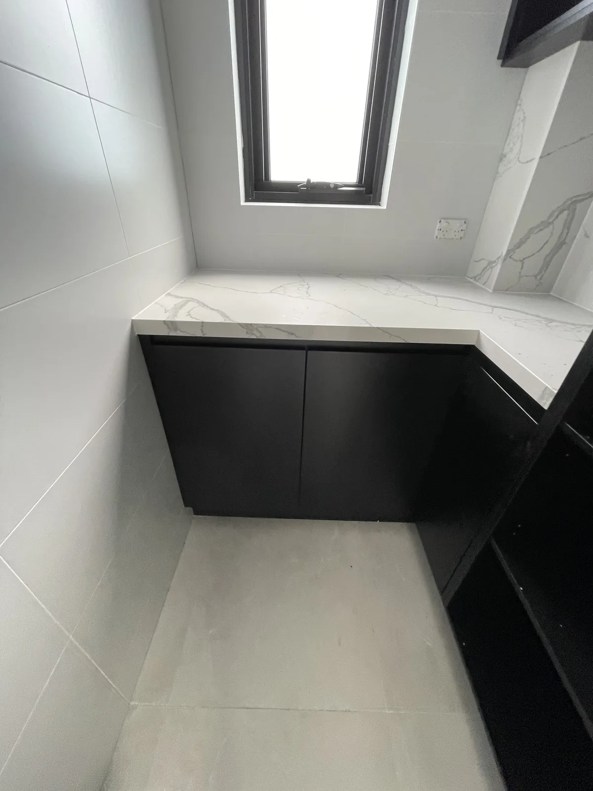 Stone bench under a window in a black walk-in pantry