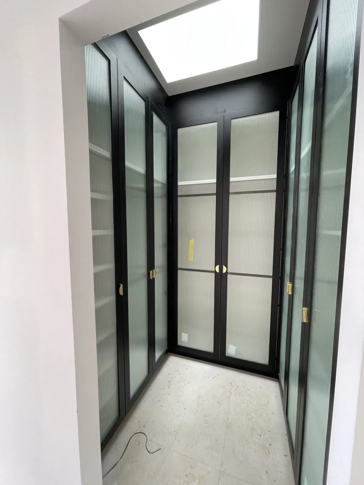 Monterey wardrobe with black framed ribbed glass doors — angle view showing depth