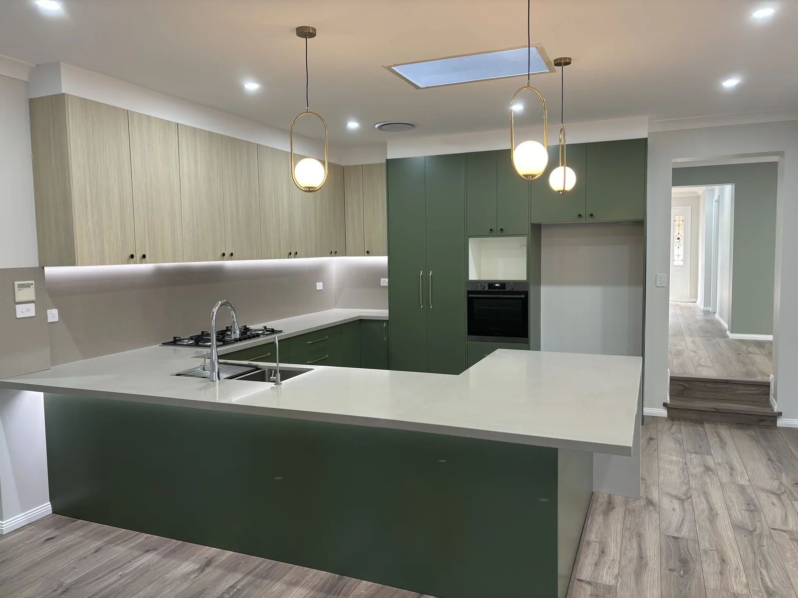 Stanhope Gardens kitchen sink and cooktop run with LED strip lighting under oak-look overhead cabinets