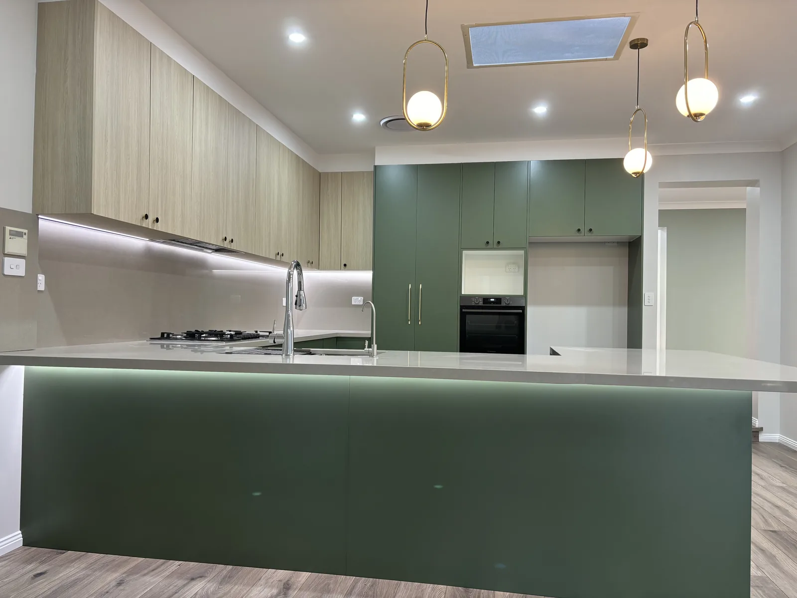 LED strip grooved into the stone benchtop edge along the dining side of a green kitchen island
