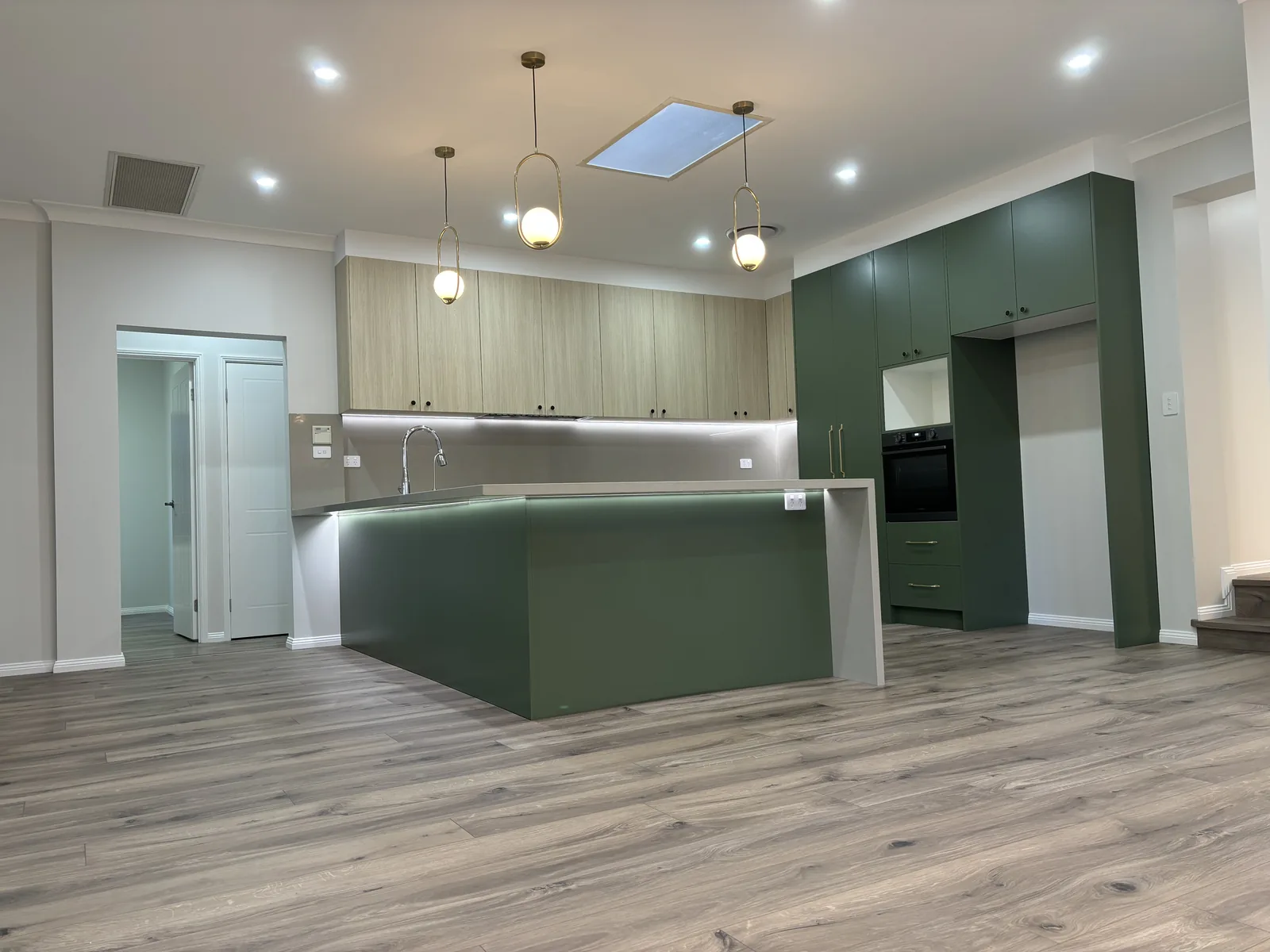 Green 2pac kitchen peninsula with white stone waterfall end and brass pendant lights