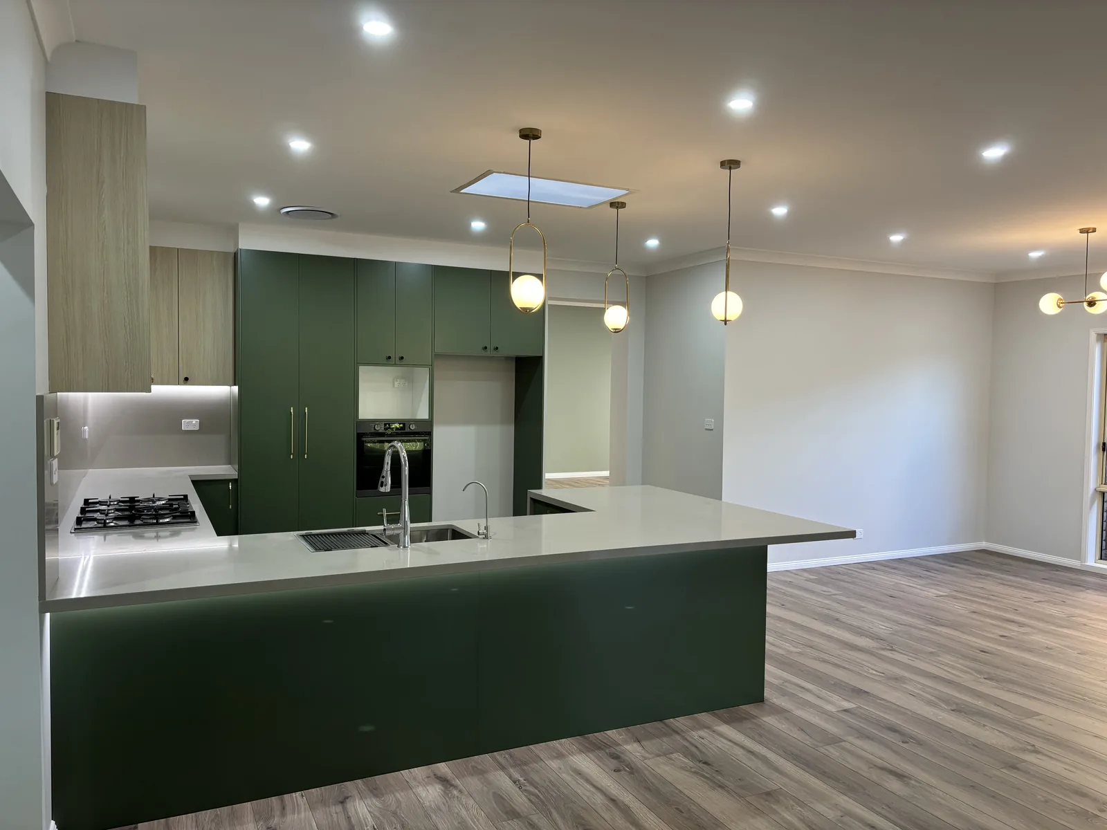 Stanhope Gardens kitchen seen from the open-plan living area with brass pendant lighting