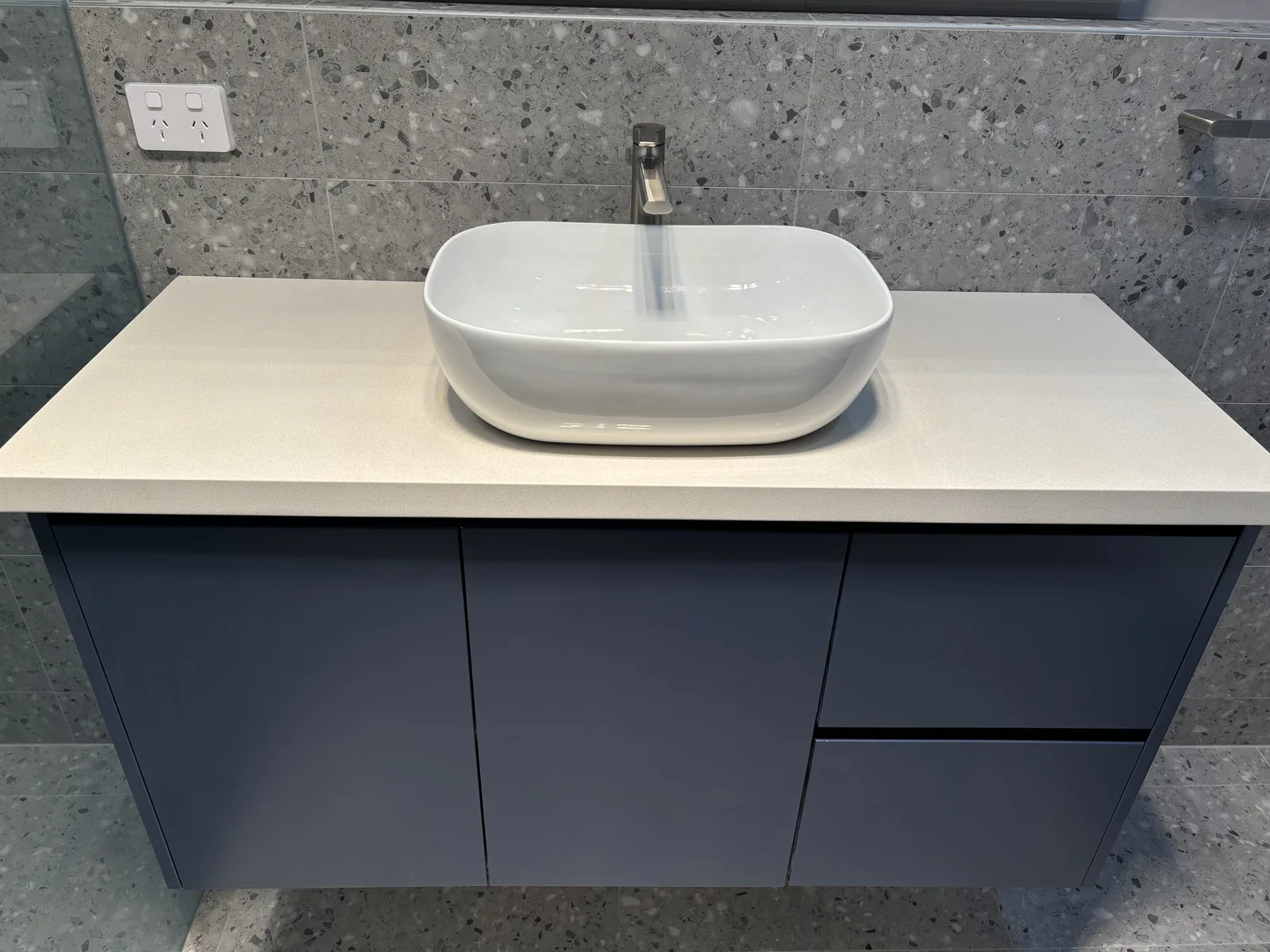 Navy floating vanity with a stone top and white above-counter basin in Stanhope Gardens