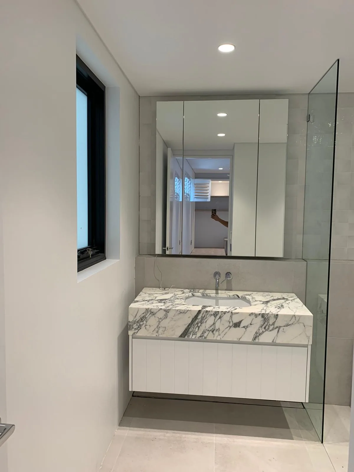 Floating vanity in white polyurethane with a stone waterfall end in Waverley