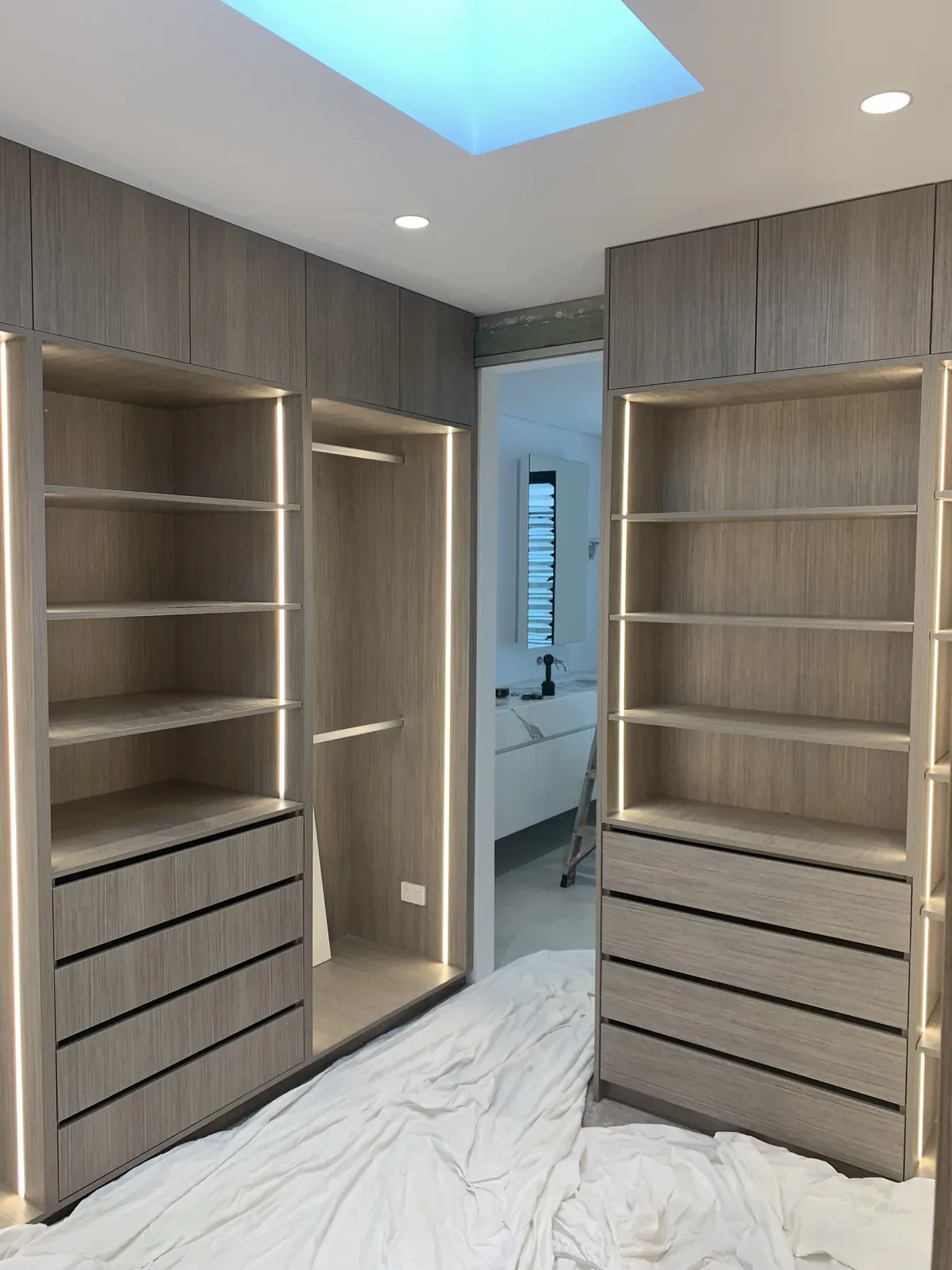 Walk-in robe drawer banks and open shelving in Polytec Manor Oak Woodmatt