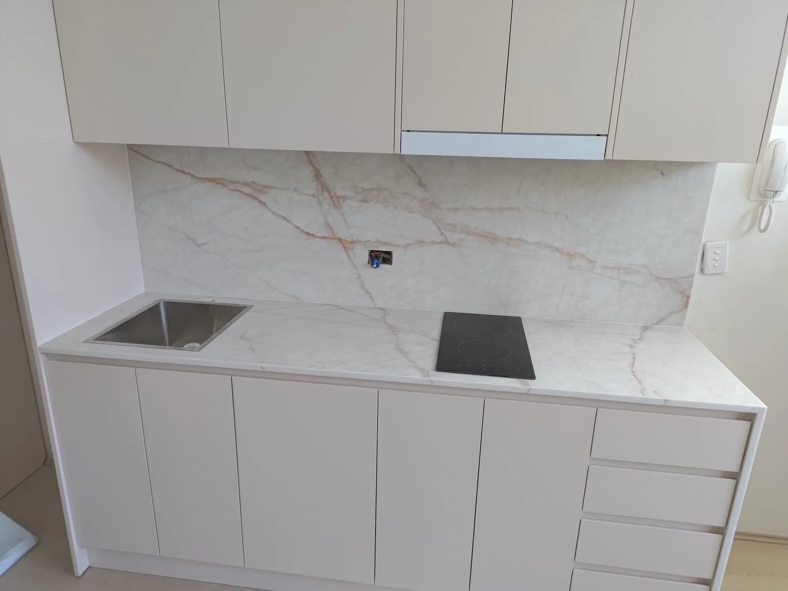 Willoughby apartment kitchen in Dulux Creamy White polyurethane with AC Stone Viola Rosse benchtop and splashback