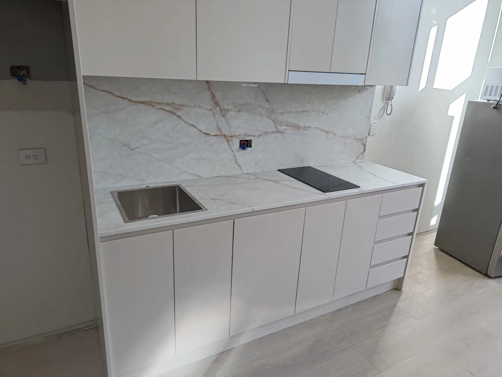 Wide view of a Willoughby apartment kitchen in Dulux Creamy White polyurethane with stone benchtop