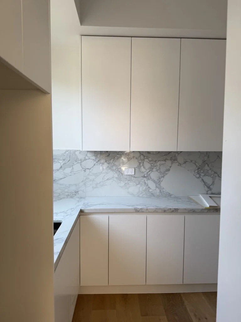 Willoughby laundry corner — full-height cabinetry with marble splashback